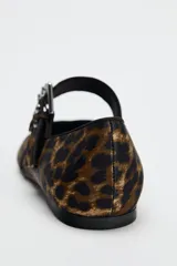 Zapato plano tipo bailarina con estampado animal, tira sobre el empeine con hebilla metálica y punta redondeada.