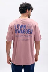 Remera manga corta color rosa con estampa azul en la espalda que dice 'I OWN SWAGGER' y coordenadas geográficas.