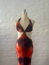 Vestido largo con estampado abstracto en tonos naranja y azul, con escote halter, espalda descubierta y aberturas laterales en la cintura.