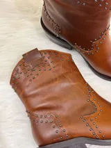 Botas cortas de cuero color marrón con punta fina, taco cuadrado y apliques de tachas metálicas.