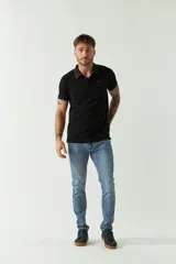 Remera polo negra de manga corta con cuello clásico, cierre de botones, bolsillo en el pecho y logo estampado.
