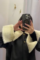 Sobre camisa marrón oscuro de paño de lana con cuello y puños de cuero de cordero color crema. Cierre frontal con botones dorados con el escudo de Uruguay.