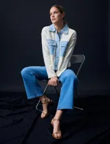 Campera combinada de punto color crema con detalles en denim celeste. Tiene cuello con solapa, cierre frontal con botones metálicos, bolsillos delanteros y corte recto.