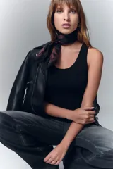 Musculosa tejida en punto rib, color negro, con hilado de viscosa y detalles de lurex, de escote redondo y calce al cuerpo.