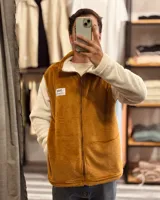 Campera marrón con mangas blancas de peluche con cierre frontal y cuello alto.