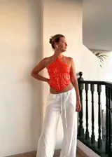 Top corto naranja con lentejuelas, escote halter y espalda descubierta. Se ata con tiras en la espalda y en el cuello.