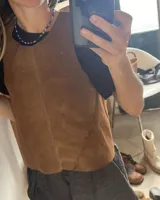 Chaleco de cuero color beige con espalda cruzada y diseño sin mangas.