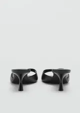 Sandalia negra de tacón bajo, con diseño minimalista y detalle en la parte superior.