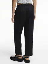 Pantalón de lino color beige, corte recto y tiro medio, con pliegues frontales y bolsillos laterales.