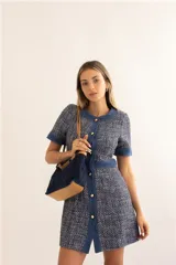 Vestido corto azul con textura tweed, cuello redondo, mangas cortas con puños de denim, cierre frontal con botones dorados y bolsillos laterales.