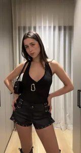 Short negro de cuerina, tiro alto, con trenzado lateral y tachas plateadas.
