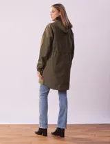 Gabardina impermeable color beige, con capucha desmontable, cierre central con cremallera y botones a presión, bolsillos delanteros y forro interno.