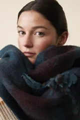 Bufanda de tejido suave y abrigado, con flecos en los extremos y diseño a rayas en tonos azul y marrón.