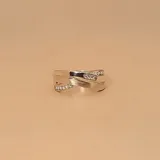 Anillo de plata 925 con diseño cruzado, donde dos bandas se entrelazan. Una de las bandas está adornada con una hilera de circonias engastadas.