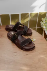 Sandalias bajas marrones con doble tira de cuero y hebilla metálica.