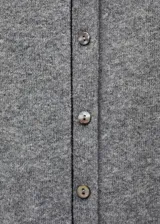 Cárdigan gris de punto fino con cuello redondo y cierre frontal con botones. Tiene costuras decorativas en negro en cuello, botones y borde frontal.