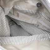 Cartera tipo hobo de cuero color taupe, con cierre superior y correa de hombro negra.