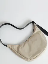 Bandolera color crema con correa larga regulable de cinta negra y logo "R" estampado en el frente.