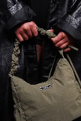 Bolso negro de nylon con textura sutil y manija fruncida.