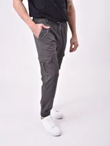 Pantalón jogger gris oscuro con cintura elástica ajustable con cordón, bolsillos laterales y bolsillo cargo con solapa en la pierna. Puños elásticos en los tobillos.