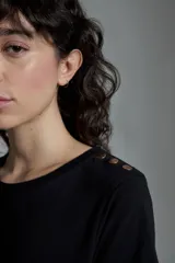 Remera blanca de manga corta con botones metálicos en el hombro, de corte clásico y diseño minimalista.
