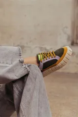 Zapatillas deportivas de cuero color beige con detalles en lila y amarillo.