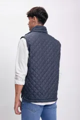 Chaleco azul marino con diseño capitoneado, cuello alto y cierre frontal con cremallera.