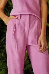 Pantalón de vestir rosado con corte recto, tiro alto y detalle de cadena dorada en la cintura.