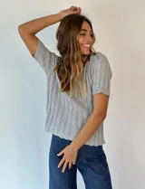 Top tejido de punto color plateado con lurex, escote redondo y mangas cortas.