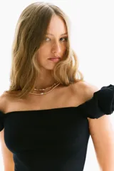 Top corto negro de punto acanalado, con hombros descubiertos y mangas cortas abullonadas con elástico revestido.