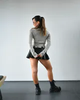 Sweater gris de punto con rayas verticales negras, cuello redondo, mangas largas con detalle de flecos y ruedo con terminación irregular.