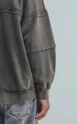 Buzo cuello redondo color gris oscuro con efecto gastado, costuras expuestas, calce oversize y roturas.