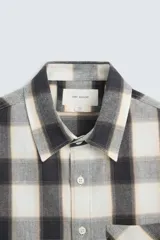 Camisa de hombre regular fit confeccionada en tejido de algodón a cuadros en tonos azul oscuro y verde oliva. Tiene cuello solapa, manga larga con puños abotonados, bolsillo de plastrón en el pecho y cierre frontal con botones.