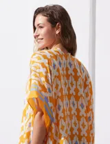 Kimono tejido color naranja con estampado geométrico en blanco y celeste, y terminación con borlas.