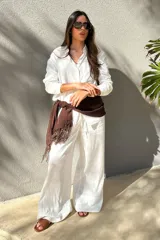 Pantalón de lino blanco de corte amplio, con cintura alta y lazo marrón con flecos.