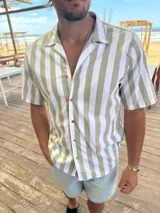 Camisa de manga corta con rayas verticales verdes y blancas, cuello clásico y cierre con botones.
