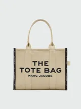 Bolso tote grande Marc Jacobs color beige con estampado del logo de la marca en negro. Tiene doble asa de mano y laterales con inscripción de la marca.