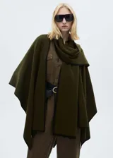 Poncho verde militar con ribete negro en contraste, cuello alto y diseño holgado. Incluye cinturón negro con hebilla dorada.