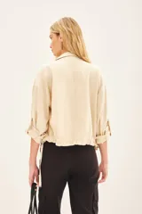 Campera marrón de lino con cierre frontal y bolsillos con solapa. Tiene mangas largas con presilla interna para arremangar.