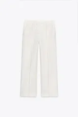 Pantalón de tiro alto color blanco, confeccionado en hilatura con viscosa, con bolsillos laterales y de plastrón en espalda. Detalle de costura marcada en delantero e hilo a contraste. Cierre frontal con cremallera, botón interior y gancho metálico.