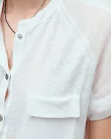 Remera celeste de lino y ramio, con corte boxy, manga japonesa, cuello mao, media cartera con broches metálicos y bolsillo plaqué con efecto de tapa.