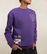 Buzo relaxed de algodón y poliéster color violeta, con cuello redondo, puños y bajo acanalados, y estampa frontal con diseño gráfico y texto.