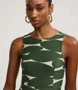Vestido midi sin mangas, de corte al cuerpo y falda plisada, con cuello redondo y cierre por gota. Presenta un estampado abstracto en verde oscuro y beige.