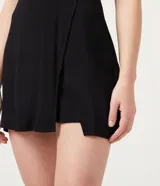 Short pollera negro de viscosa con cierre de cremallera trasero, corte mini y diseño cruzado con abertura frontal.