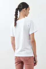 Remera blanca de algodón con cuello redondo y mangas cortas. Estampado rectangular con diseño floral y geométrico en tonos rojos, azules y amarillos.