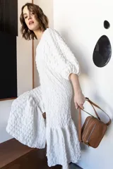 Bandolera rectangular de cuero color nude con doble compartimento con cierre de cremallera plateada y correa de cuero ajustable.