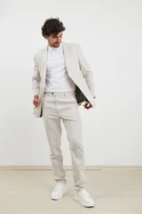 Saco beige de corte clásico, con solapas de muesca, cierre de dos botones y bolsillos laterales con solapa.