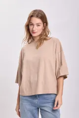 Remera color beige de corte holgado, con cuello alto y mangas 3/4.