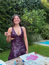 Vestido corto de lentejuelas color verde oliva, con escote en V, breteles finos cruzados en la espalda, cut-outs laterales y volado en el ruedo.