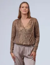 Blusa en microtul con bordado de lentejuelas, escote en V cruzado y ruedo elastizado.
